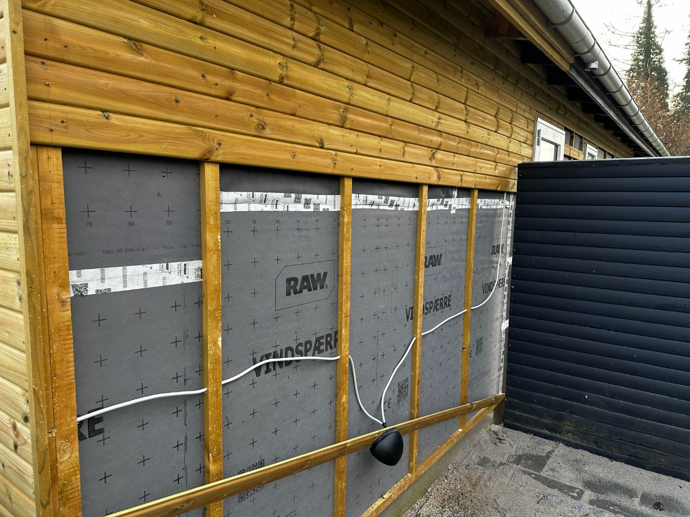 Udehus under opbygning med vindspærre og træbeklædning